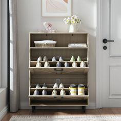 a wooden shoe rack filled with shoes next to a white door in a living room