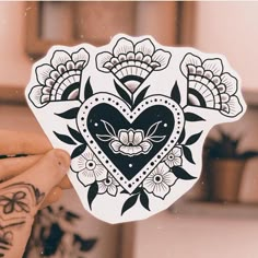 a person holding up a sticker with an image of a heart and flowers on it