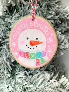 a christmas ornament hanging on a tree in front of a snowman's head