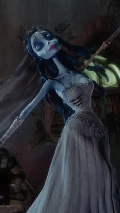 a woman in a white dress with blue makeup and long hair is holding a stick