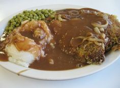 a white plate topped with meat, mashed potatoes and gravy covered in gravy