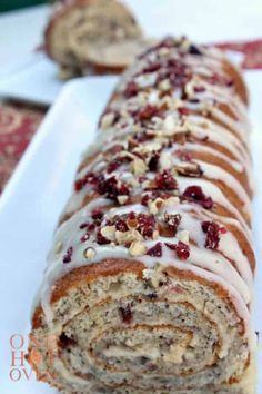 a banana roll cake with cranberries and pecans on top is sitting on a white plate