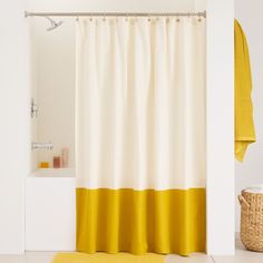 a yellow and white shower curtain next to a bathtub with a towel on it