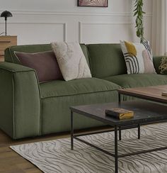 a living room with green couches and pillows on the floor next to a coffee table