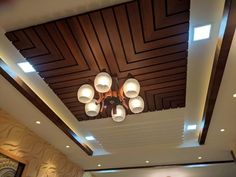 the lights are on in this room with wood paneling and white ceiling tiles, along with decorative wallpaper