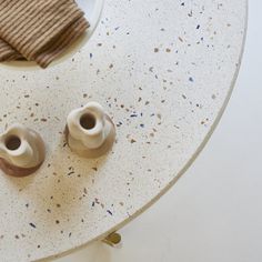 two white vases sitting on top of a table next to a brown hat and napkin