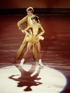 two people are skating on an ice rink with their arms around each other's shoulders