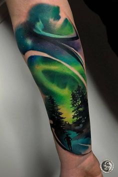 a man's arm with an aurora bore tattoo on it and trees in the background