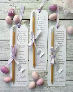 three tags with easter eggs and pencils attached to them on a wooden table next to flowers