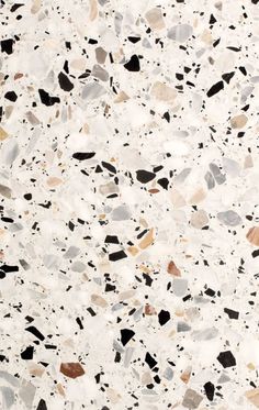 a white and black speckled surface with lots of different colored rocks on it's sides