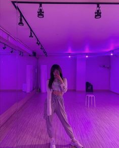 a woman taking a selfie in an empty room with purple lights on the walls