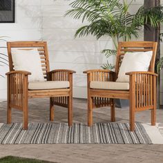 two wooden chairs sitting next to each other on top of a rug in front of a house