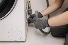 a man is working on an appliance in front of a washing machine