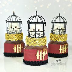 three small birdcages are decorated with gold chains and monogrammed letters on them