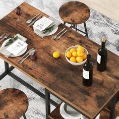 a wooden table topped with plates and bowls filled with oranges next to wine bottles