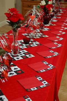 the table is set up with cards and vases filled with red roses, flowers in clear vases