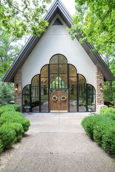 the entrance to a house with an arched door and glass windows, surrounded by greenery