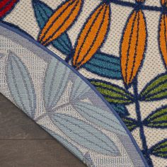 closeup of an area rug with orange and blue flowers on it, sitting on a wooden floor