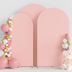 a teddy bear sitting next to a pink wall with balloons on it's sides