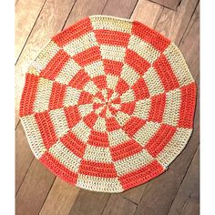 a red and white crocheted rug on the floor with wood floors in the background