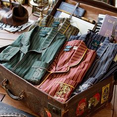 an open suitcase filled with clothes on top of a wooden table