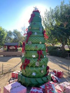 a very large christmas tree made out of many wrapped presents in front of some trees