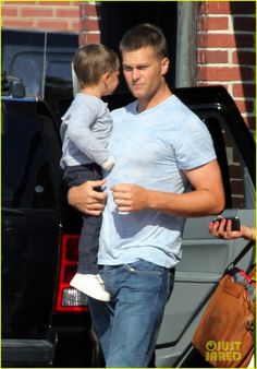 a man holding a small child in his arms while walking past a truck with the door open