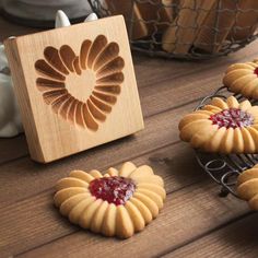 some cookies are sitting on a table next to a wooden box with jelly in it