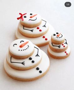 three decorated cookies sitting next to each other on top of a white tablecloth covered surface