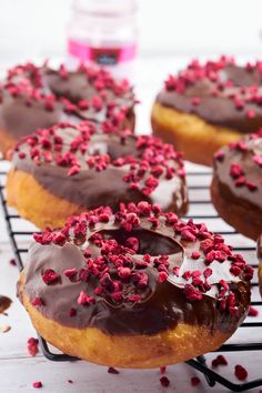 chocolate frosted donuts with sprinkles on a cooling rack, ready to be eaten