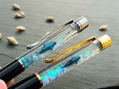 three pens with different designs on them sitting next to each other in front of shells