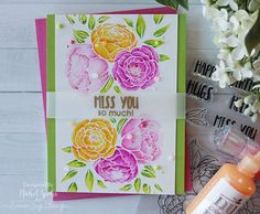 a close up of a card on a table with flowers and a bottle of glue