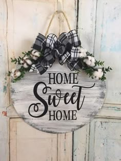 a wooden sign that says home sweet and some cotton flowers hanging from the front door