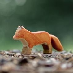 a small wooden toy fox standing on top of leaves