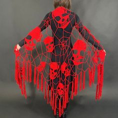 a woman in a black and red costume with skulls on her back, holding onto the sides of her arms