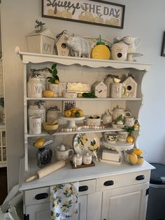 a white china cabinet filled with dishes and lemons