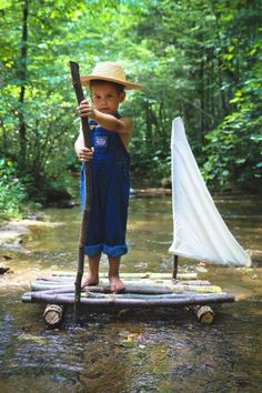 a young boy is standing on a raft in the middle of a river with an umbrella