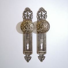 two ornate silver door handles on a white wall