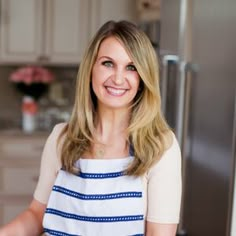 a woman standing in front of a kitchen counter holding a knife and smiling at the camera