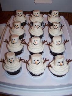 cupcakes with frosting and snowmen on them sitting on a white tray