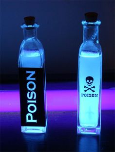 two glass bottles with skull and crossbones on them, one is blue and the other is pink