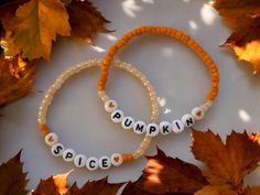 two bracelets that say pumpkin spice in white letters on orange and brown beads, surrounded by leaves