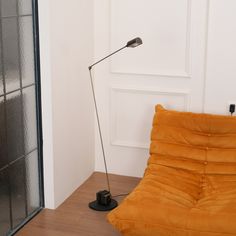 a floor lamp sitting on top of a wooden floor next to a yellow futon