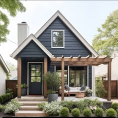 a blue house with white trim and wooden steps leading up to the front door is surrounded by greenery