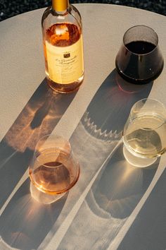 two wine glasses sitting on top of a white table next to a bottle of wine