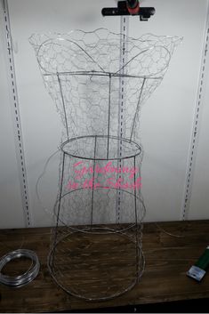 a wire basket with pink writing on it sitting on top of a wooden table next to a door