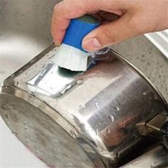 a person using a blue and white brush to clean a metal trash can in a sink