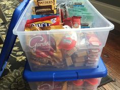 a plastic container filled with snacks on top of a wooden floor next to a blue chair