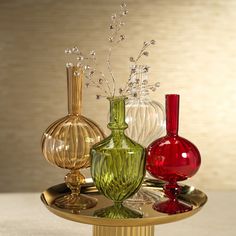 three different colored vases sitting on top of a gold plated tray with flowers in them