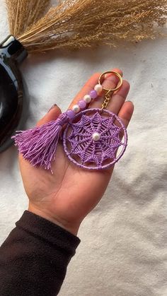 a hand holding a purple keychain with beads and tassels